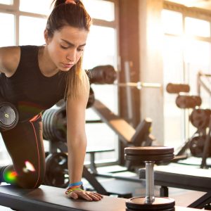 young woman lifting barbell - three point row