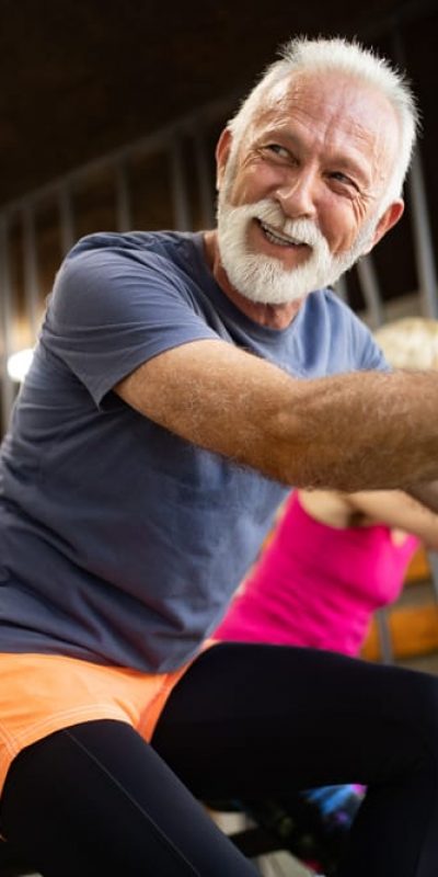 fit older man smiling on exercise bike