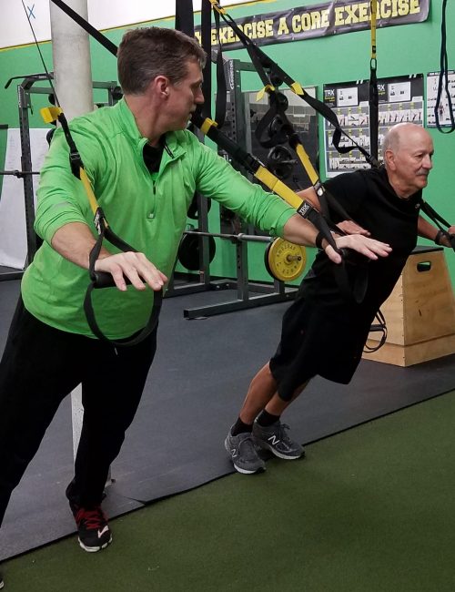 John of Thrive Fitness showing client how to use TRX